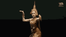 a woman in a gold dress is dancing in front of a black background .