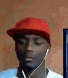 a man wearing a red hat and ear buds is looking at a computer screen .
