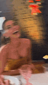 a blurry photo of a woman sitting at a table with a plate of food .