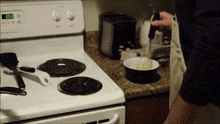 a person is cooking on a stove that has the time of 3:08