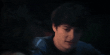 a close up of a young man 's face in a dark room looking at the camera .