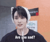 a young man wearing a knitted hat and a black shirt says are you sad
