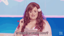 a woman in a pink dress is holding a lollipop and asking is this the world now .