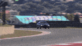 a blue car is driving down a race track with a large screen behind it that says ' fox '