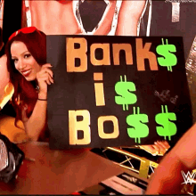 a woman holding a sign that says " banks is boss "