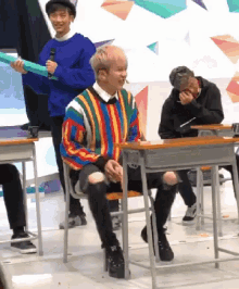 a man in a striped sweater sits at a desk