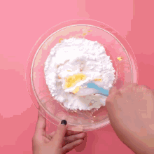 a person is mixing ingredients in a bowl with a blue spatula .
