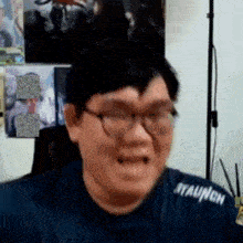 a man wearing glasses is making a funny face while sitting in front of a computer .