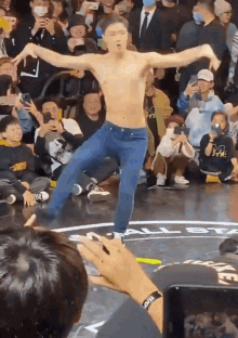 a man without a shirt is dancing in front of a crowd that is watching him