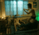 a man without a shirt is standing on a bed next to another man without a shirt