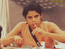 a woman sitting at a table with her finger to her mouth and the words goodvibesmode on the bottom right