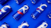 several blue cans of cola are laying on a blue surface