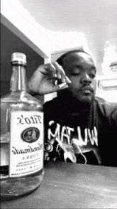 a man smoking a cigarette next to a bottle that says ' 2011 ' on it