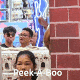 a group of people standing in front of a brick wall with the words peek-a-boo written on the bottom