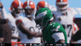 a football player wearing a green helmet stands in a huddle with his teammates