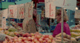 a man and a woman are standing in front of a fruit stand with a sign that says 9.99 on it
