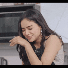 a woman is making a funny face in a kitchen while holding her hand to her face .