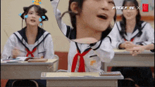 a girl in a sailor suit is sitting at a desk in a classroom with a free fire x logo on the screen