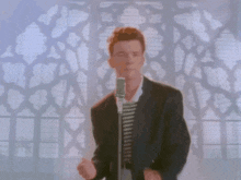 a man in a suit singing into a microphone in front of a window