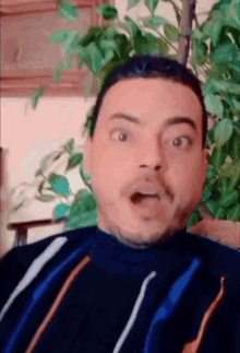 a man with a surprised look on his face is wearing a striped sweater .