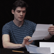 a man in a blue striped shirt is reading a letter
