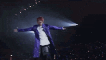 a person in a purple jacket is making a heart with their hands .
