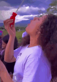a woman blowing soap bubbles with a red bottle
