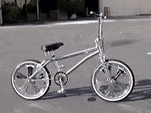 a silver bicycle is parked on the side of a road .
