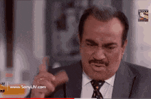 a man in a suit and tie is giving a thumbs up sign