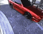 a red car is parked on a snowy road