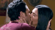 a man and a woman are kissing each other in a living room .