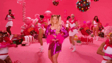 a woman in a pink dress is dancing in front of a pink background