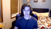 a man wearing headphones looks at the camera in a bedroom
