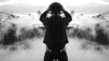 a black and white photo of a man looking at mountains