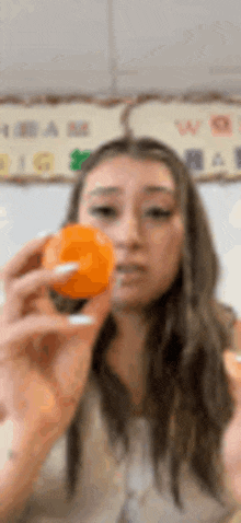a woman is holding an orange in her hand and looking at it .
