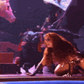 a woman with red hair is laying on the ground in front of a crowd