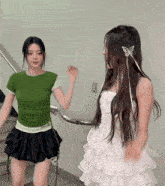 a woman in a green shirt and a woman in a white dress are dancing together