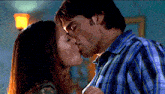 a man and a woman are kissing and the woman is wearing a blue plaid shirt