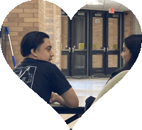 a man and a woman are sitting at a table in front of a door that says 26
