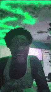 a woman in a white tank top is laughing under a green light