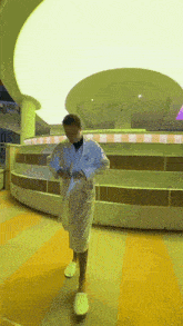 a man in a white robe and white slippers is standing in a room with a ceiling that has a circle in it