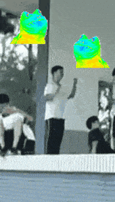 a man in a white shirt is standing in front of a window with a green and yellow cat flying in the air behind him