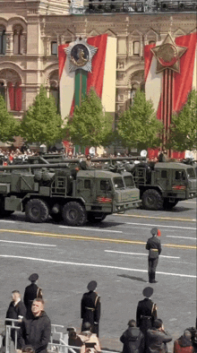 a row of military vehicles are parked in front of a large building