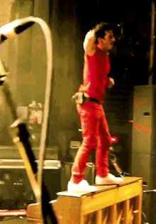 a man in red is standing on a piano