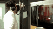 a man is wearing headphones and singing into a microphone .