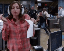 a woman wearing headphones is holding a piece of paper in a room .