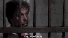 a man is behind bars in a jail cell saying `` hey , words hurt . ''