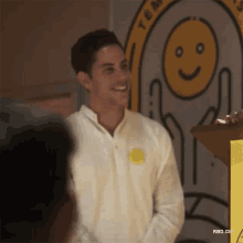 a man in a white shirt is standing in front of a podium with a smiley face on it .