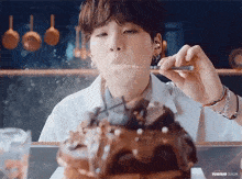 a person is eating a cake with a spoon and blowing smoke out of it .