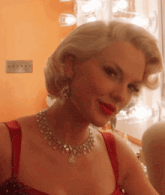 a woman wearing a necklace and red lipstick